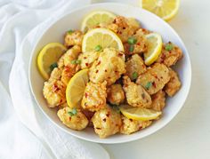 a white bowl filled with chicken and lemons