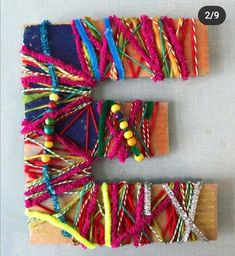 the letters k are made out of different colored yarns and wooden sticks with beads on them