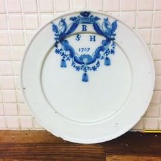 a blue and white plate sitting on top of a wooden floor next to a tiled wall