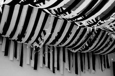 black and white photograph of the inside of a building with many striped structures hanging from it's ceiling