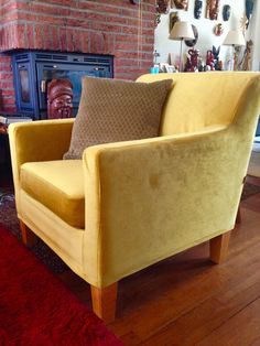 a yellow chair sitting on top of a wooden floor in front of a fire place