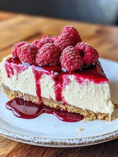 a piece of cheesecake with raspberries on top is sitting on a plate