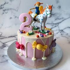 a birthday cake decorated with the number two and horse figurines