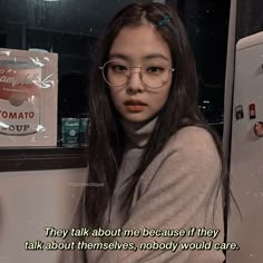 a girl with glasses standing in front of a refrigerator freezer next to a sign that says, they talk about me because if they talk about themselves, nobody would care