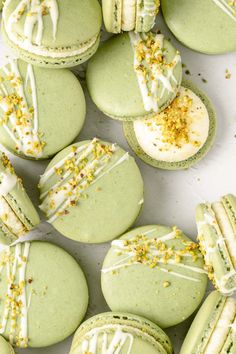 green macaroons with white frosting and sprinkles on them are arranged in rows