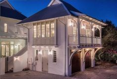 a large white house with lots of windows and shutters on the front door is lit up at night