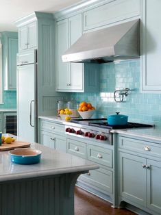 a kitchen with blue cabinets and white counter tops, an island in the middle has fruit on it