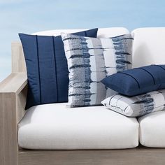 the pillows are stacked on top of each other in front of a white couch with blue accents