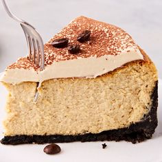 a piece of cake with white frosting and chocolate chips on top is being cut by a fork