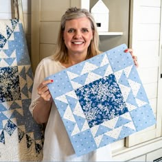 a woman holding up a blue and white quilt