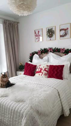 a cat sitting on top of a white bed in a room with christmas decorations and lights