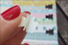 a woman's hand with red nail polish holding a piece of white plastic material