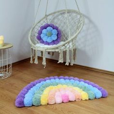 a rainbow rug is sitting on the floor next to a hanging chair with a flower