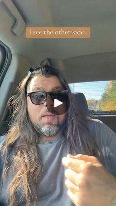 a man with long hair and sunglasses sitting in the back seat of a car talking to someone