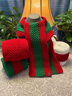 a red and green sweater sitting on top of a table next to two rolls of yarn