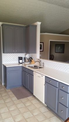 a kitchen with gray cabinets and white counter tops