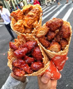 three cones filled with different types of food on top of each other in front of a street