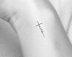 a woman's arm with the word faith on it and a cross in the middle