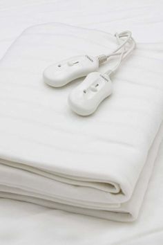 two electric hair dryers sitting on top of white sheets