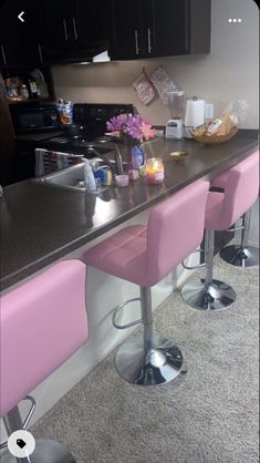 three pink bar stools sitting in front of a counter