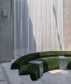 a green curved couch sitting in front of a window