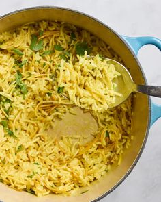 a pot filled with yellow rice and garnished with parsley