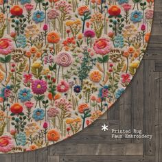 a close up of a piece of fabric with flowers on it and a wooden background