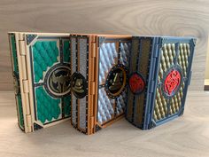 three books with decorative designs on them sitting on a wooden table next to each other