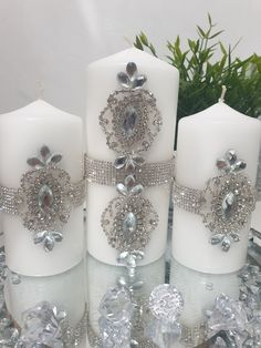 three white candles with crystal decorations on them