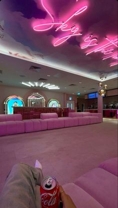 a pink couch sitting in the middle of a living room next to a neon sign