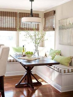 a dining room table and bench in front of two windows