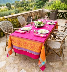 an outdoor table set for two with plates and glasses on it, overlooking the countryside