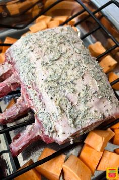 a piece of meat sitting on top of a grill next to sweet potatoes and carrots