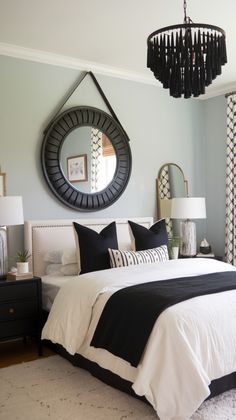 a bedroom with black and white bedding, chandelier and mirror on the wall