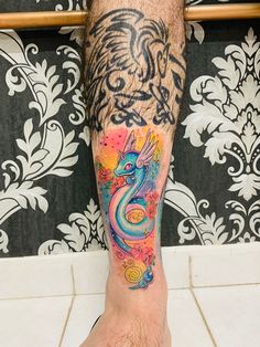 a man's leg with a colorful dragon tattoo on his left leg and foot