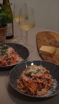 two plates of spaghetti with parmesan cheese and wine