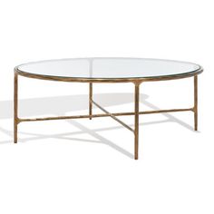 an oval glass coffee table with gold frame and metal legs, against a white background