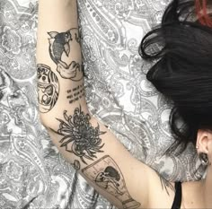 a woman laying on top of a bed with tattoos on her arm and arms,