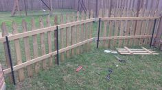 a wooden fence with tools laying on the ground next to it in a backyard area