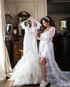 a woman standing next to a dress on a hanger in front of a mirror