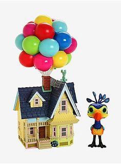 a dollhouse with balloons and a bird next to it