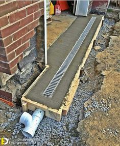 a drain pipe laying on the ground next to a brick wall and some concrete pipes