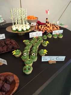 a table topped with lots of cupcakes covered in green frosting