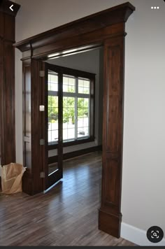 an empty living room with wood floors and large wooden pillars in the middle of it