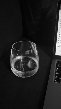 an open laptop computer sitting on top of a table next to a glass filled with water