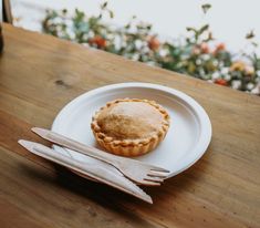 there is a small pie on the plate next to a fork and knife sitting on the table