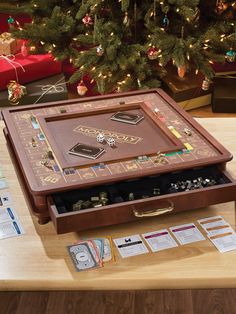 a wooden table topped with a game board and lots of other items next to a christmas tree