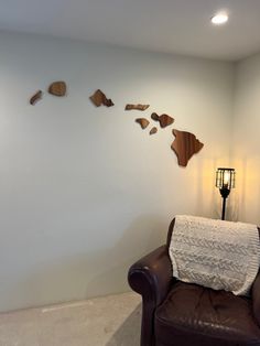 a brown leather chair sitting in front of a white wall with wooden pieces on it