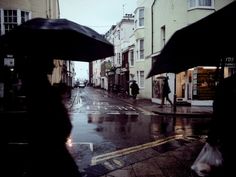 black and white photograph of people walking in the rain with umbrellas