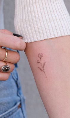 a woman with a small flower tattoo on her arm